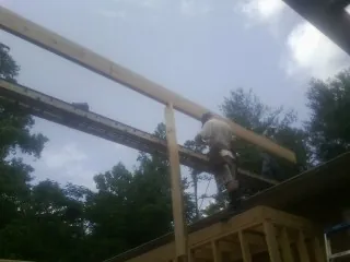Carpenter setting a ridge beam over a new addition frame — Ice Dam Removal by Roofing Brothers in North Baltimore