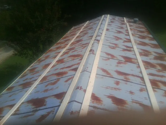 Rusted metal roof panels with new wood purlins before replacement — Storm Damage Roof Repair in North Baltimore by Roofing Brothers