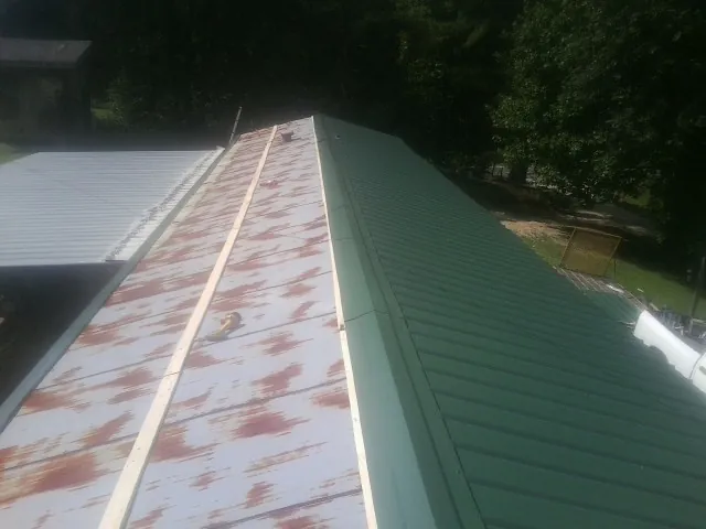 Old rusted panels beside newly installed green metal roofing — Wind Damage Roof Repair by Roofing Brothers in North Baltimore