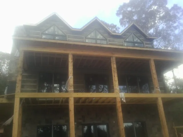 Dormers and porch framing on a large log home under construction — Roof Coating work by our crew in North Baltimore
