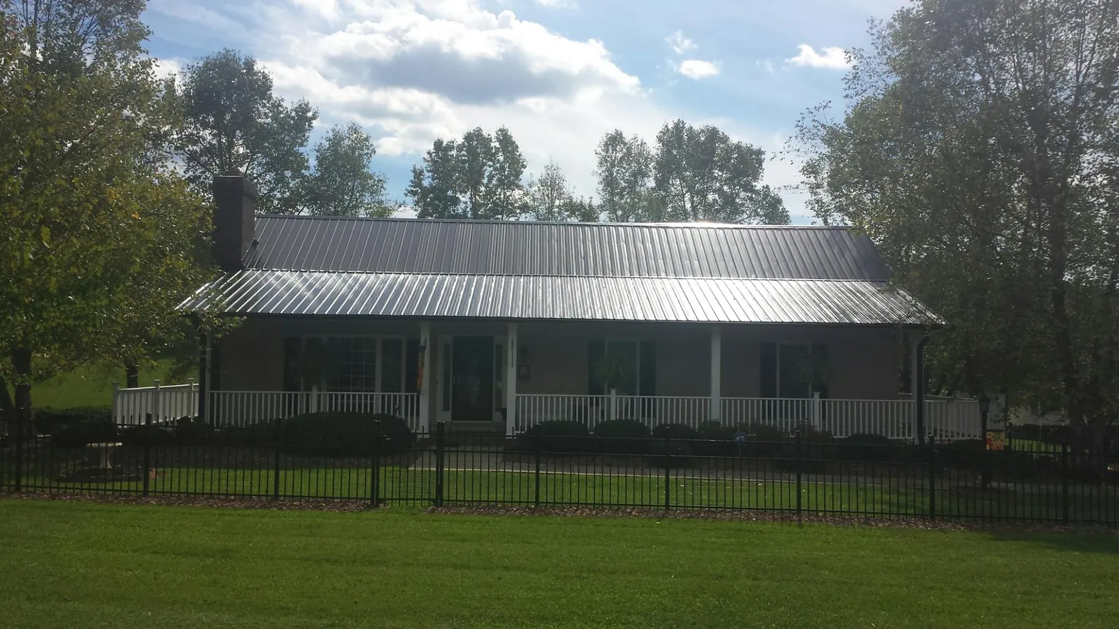 Gray metal roof on a brick ranch with a full width front porch — Gutter Guard Installation work by our crew in North Baltimore