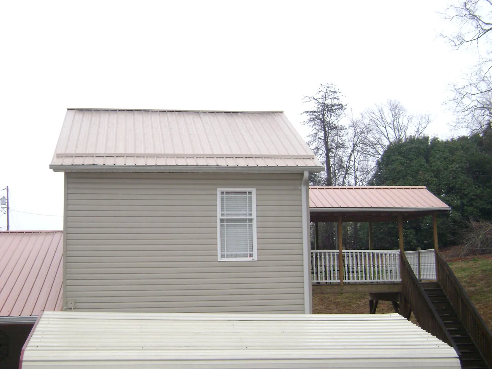 Tan metal roofs on a two story addition and attached porch, from a Roof Replacement job in North Baltimore