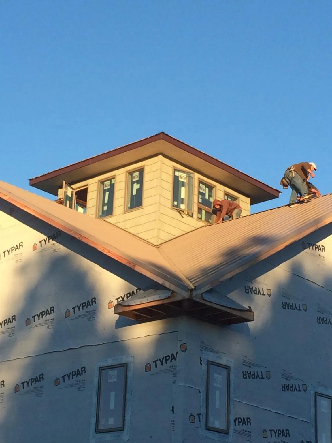 Roofers working around a rooftop cupola on a new metal roof at sunset — Roof Waterproofing in North Baltimore by Roofing Brothers